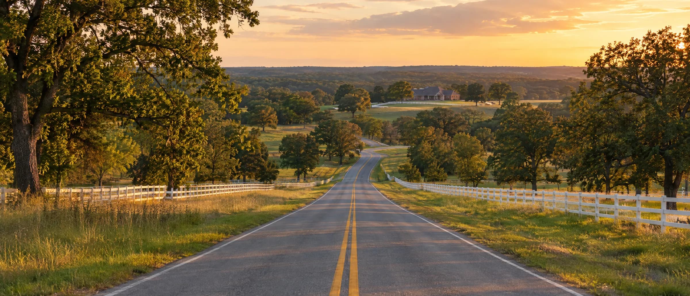 Two-lane country road through Northeastern Oklahoma pasture at sunset